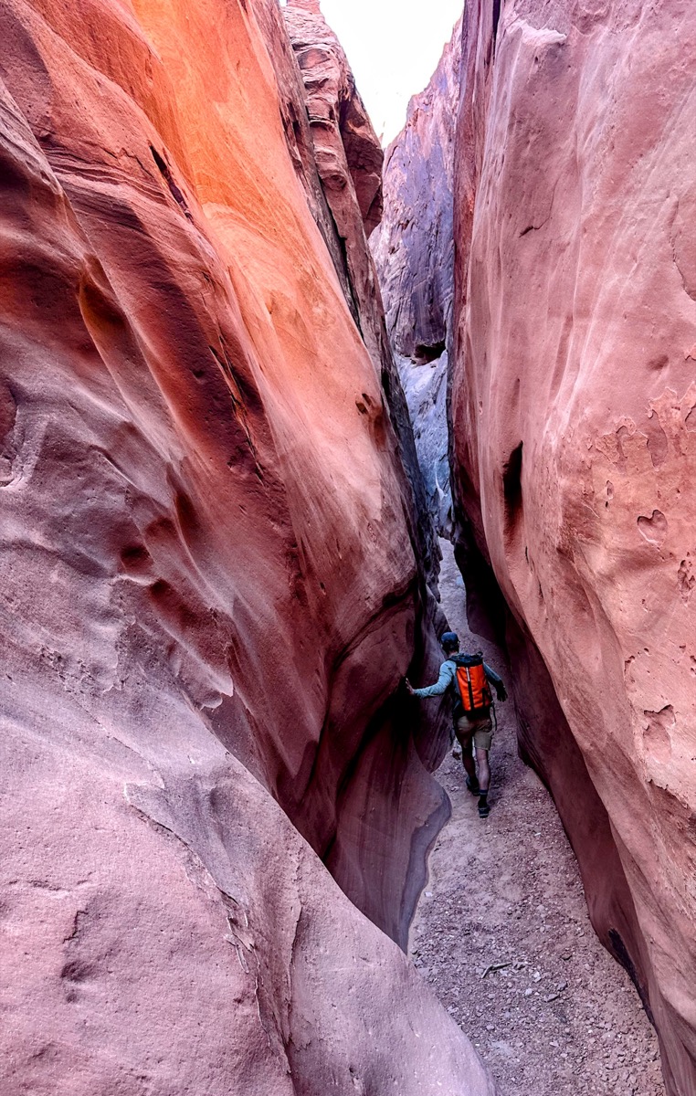 Hiker navigating the narrow sandstone fins of the Fiery Furnace, Arches National Park